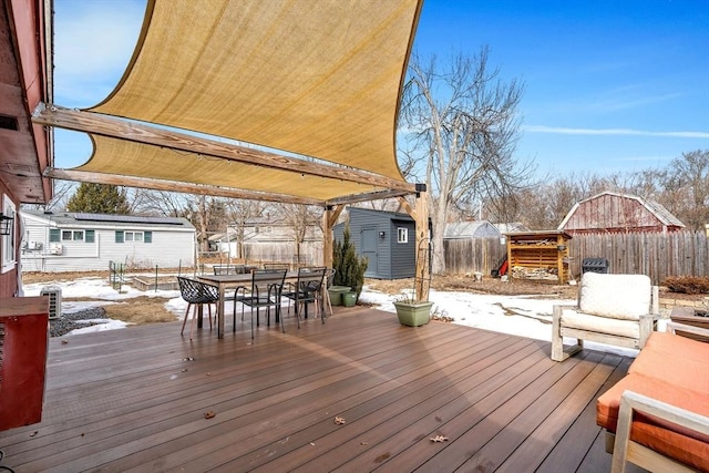 wooden deck with an outbuilding, a shed, outdoor dining space, and a fenced backyard