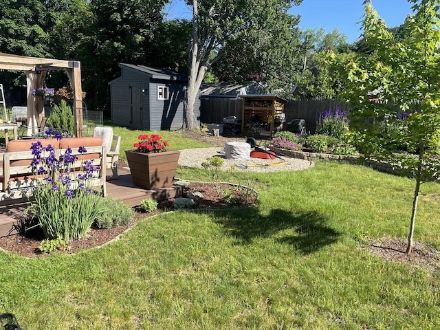 view of yard with a shed, fence, a wooden deck, and an outdoor structure