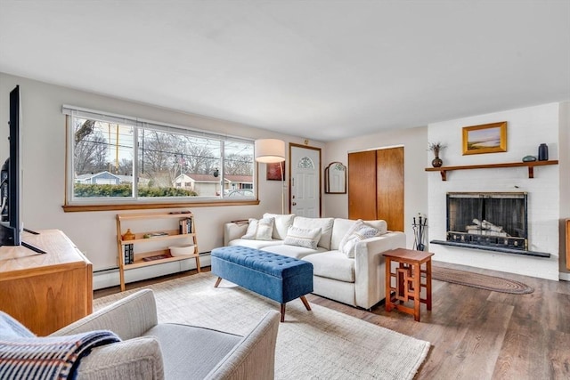 living room featuring a baseboard radiator, a fireplace, and wood finished floors