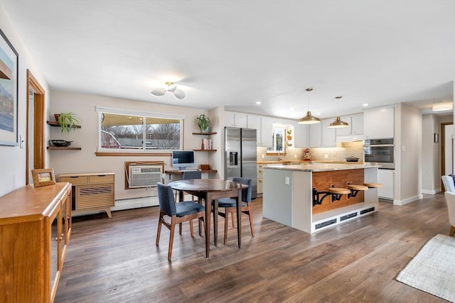 dining space featuring a baseboard radiator, dark wood-style flooring, a healthy amount of sunlight, and recessed lighting