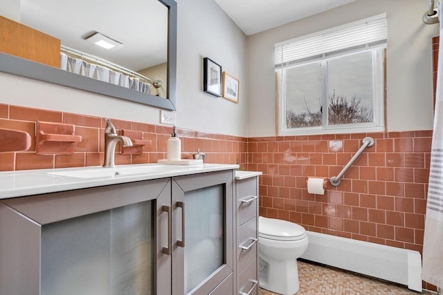 bathroom with toilet, wainscoting, tile walls, and vanity