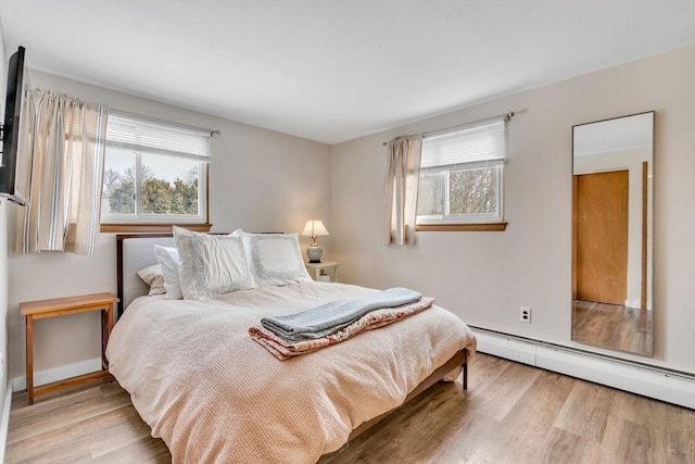 bedroom with baseboard heating and wood finished floors