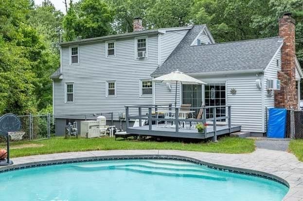 rear view of property featuring a pool side deck and a yard