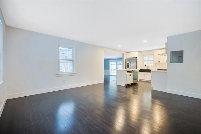 unfurnished living room featuring sink, electric panel, and dark hardwood / wood-style flooring