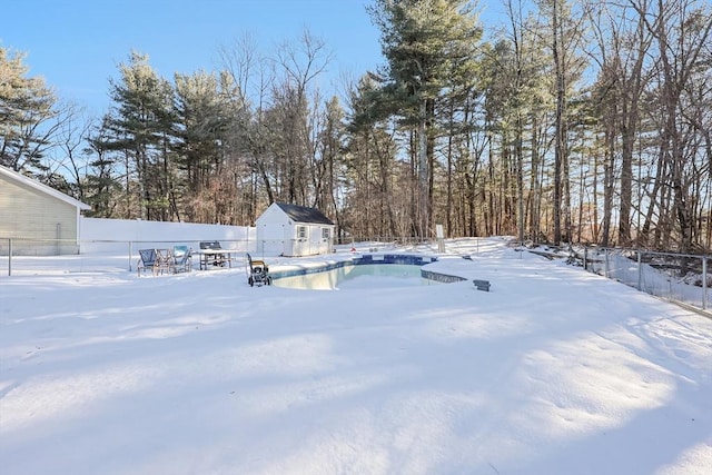 yard covered in snow with a shed and a fenced in pool