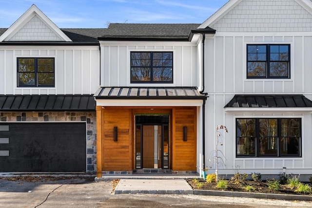 view of front of house featuring an attached garage, a standing seam roof, a shingled roof, and board and batten siding