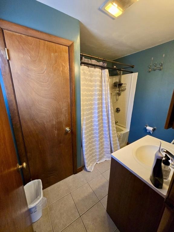 bathroom with tile patterned floors, shower / bathtub combination with curtain, and vanity