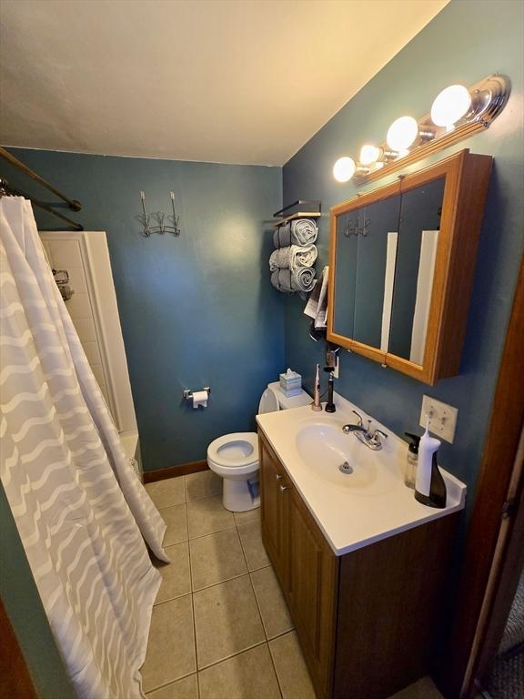 full bath with tile patterned flooring, vanity, toilet, curtained shower, and baseboards