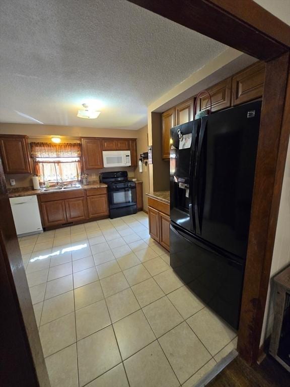 kitchen featuring black appliances, light tile patterned floors, a textured ceiling, brown cabinets, and light countertops