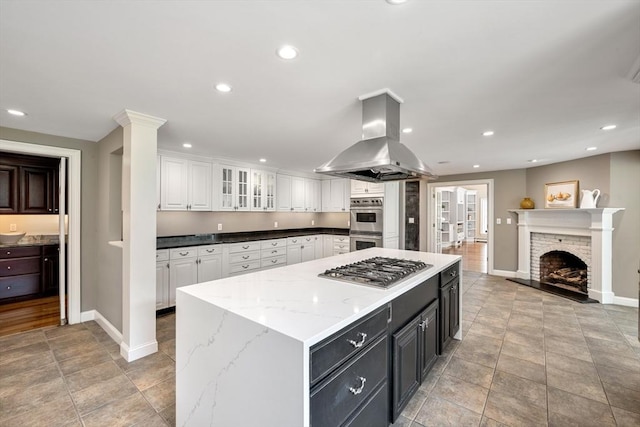 kitchen with island range hood, white cabinetry, baseboards, appliances with stainless steel finishes, and recessed lighting