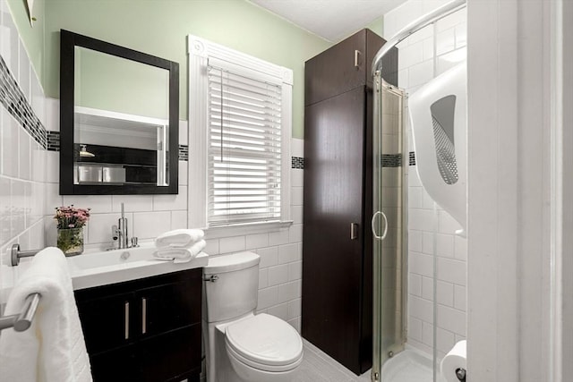 full bathroom with toilet, a stall shower, vanity, and tile walls