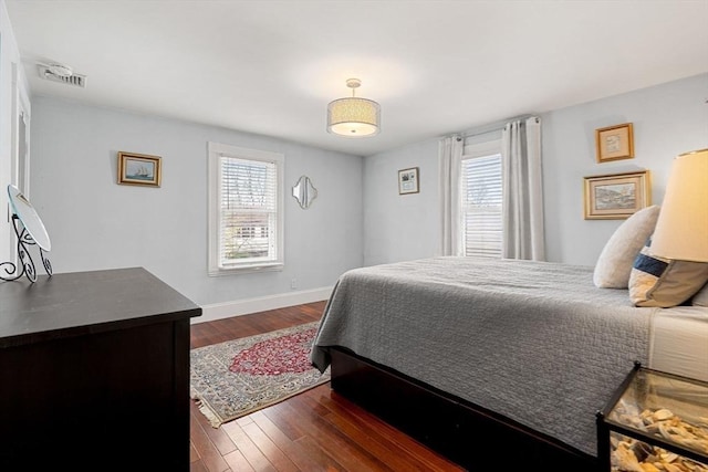 bedroom with dark wood-style flooring, visible vents, and baseboards