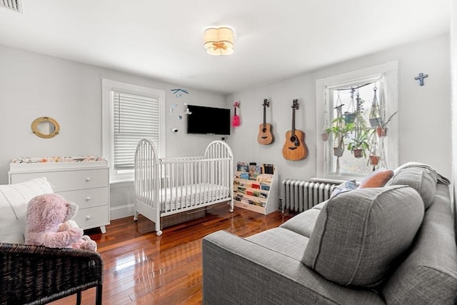 bedroom featuring baseboards, visible vents, dark wood finished floors, and radiator heating unit