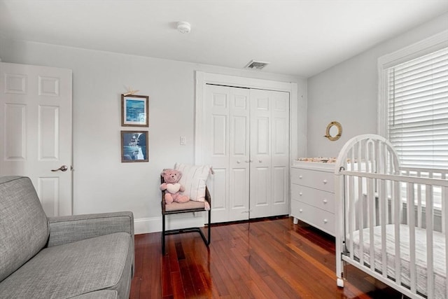 bedroom featuring dark wood-type flooring, a closet, visible vents, and baseboards