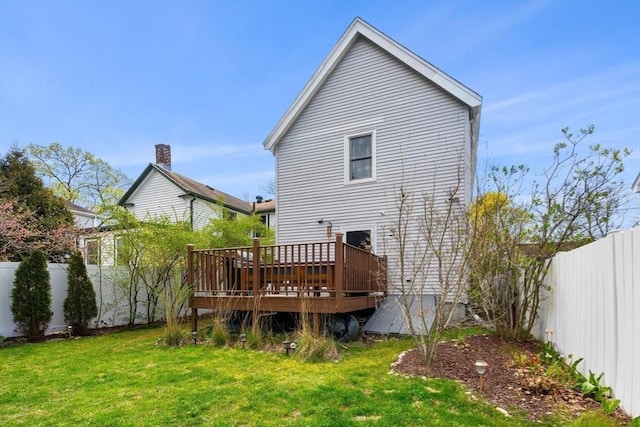 back of property with a fenced backyard, a wooden deck, and a yard