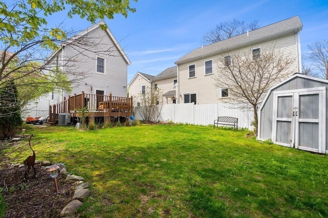 rear view of house featuring a deck, cooling unit, a storage shed, an outdoor structure, and fence