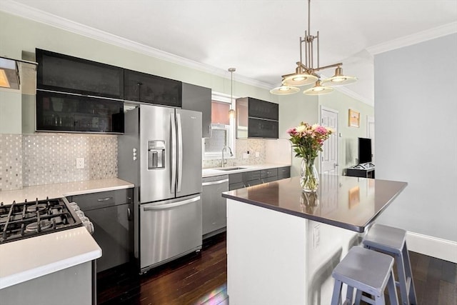 kitchen featuring a kitchen island, decorative light fixtures, stainless steel appliances, crown molding, and a sink