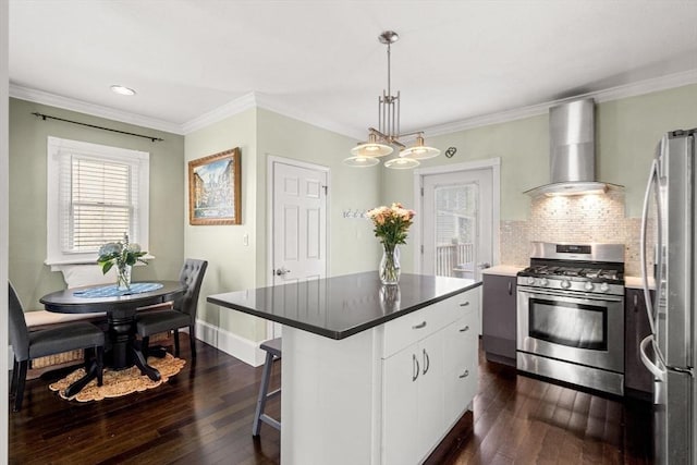 kitchen with a center island, a breakfast bar area, appliances with stainless steel finishes, white cabinetry, and wall chimney range hood