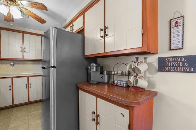 kitchen with white cabinetry, ceiling fan, and stainless steel refrigerator