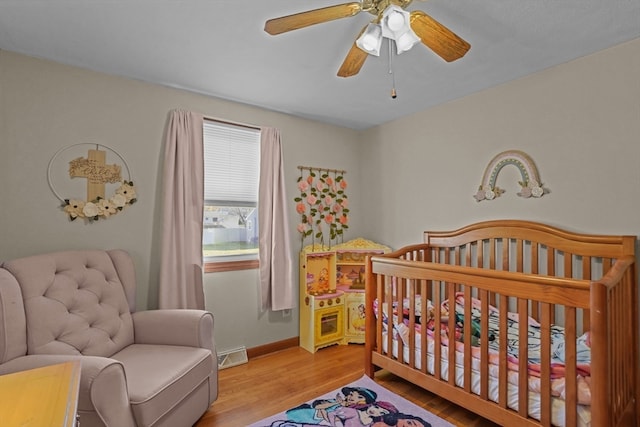 bedroom with light hardwood / wood-style flooring, a nursery area, and ceiling fan