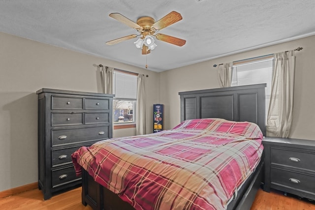 bedroom featuring ceiling fan, light hardwood / wood-style flooring, and a textured ceiling