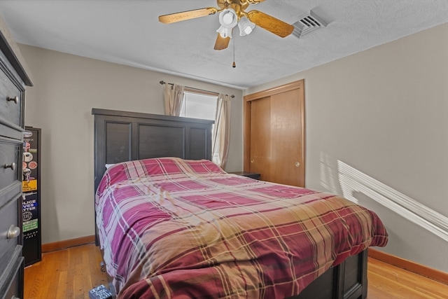 bedroom with ceiling fan, light hardwood / wood-style flooring, and a textured ceiling