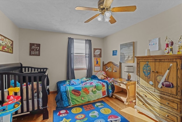 bedroom featuring ceiling fan, wood-type flooring, and a textured ceiling