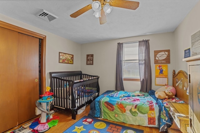 bedroom with wood-type flooring, a textured ceiling, a closet, and ceiling fan