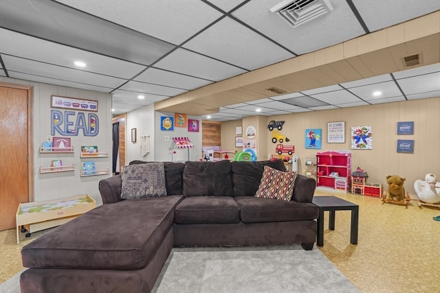 carpeted living room with a paneled ceiling and wood walls