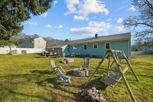 back of house with a playground, a yard, and an outdoor fire pit