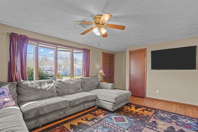 living room featuring ceiling fan, wood-type flooring, and a textured ceiling