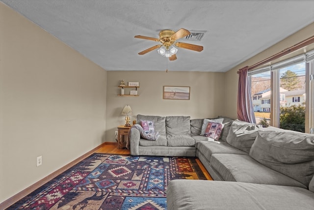 living room featuring ceiling fan, a textured ceiling, and hardwood / wood-style flooring