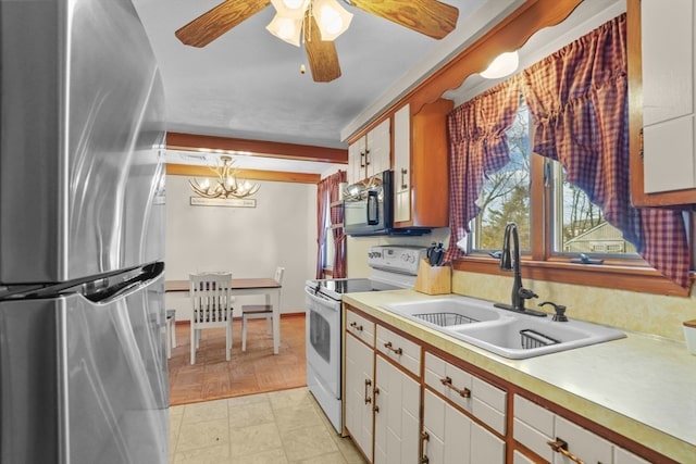 kitchen featuring pendant lighting, white cabinets, sink, white electric range oven, and stainless steel refrigerator