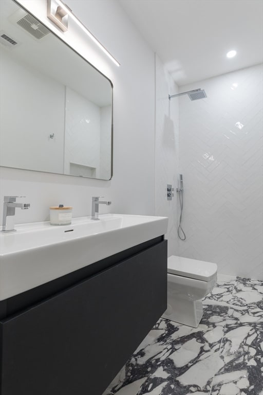 bathroom featuring toilet, vanity, and tiled shower