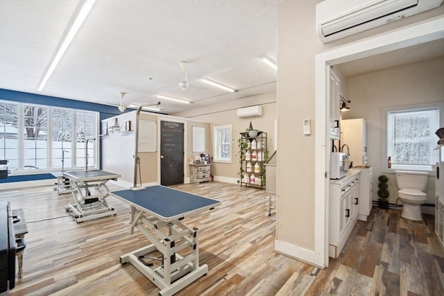 gym with wood-type flooring and a wall unit AC