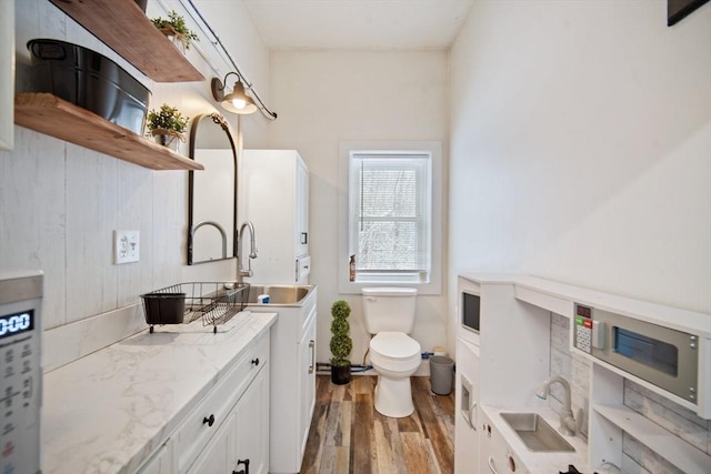 bathroom featuring toilet, wood-type flooring, and sink