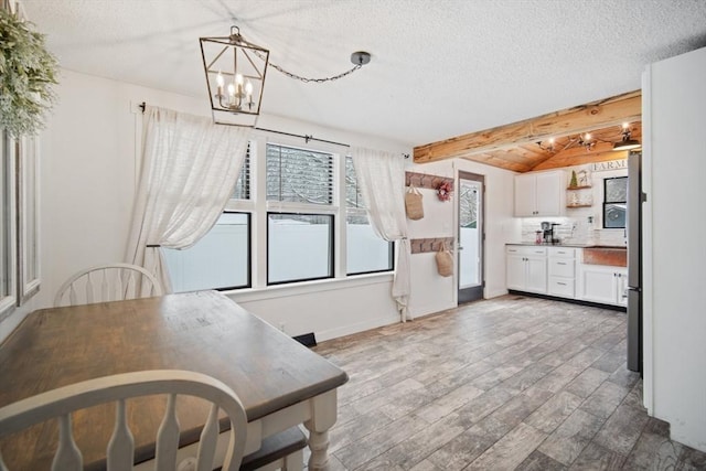 kitchen featuring pendant lighting, white cabinets, a textured ceiling, vaulted ceiling with beams, and decorative backsplash