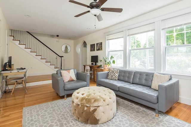 living room with light wood finished floors, arched walkways, stairs, ceiling fan, and a desk