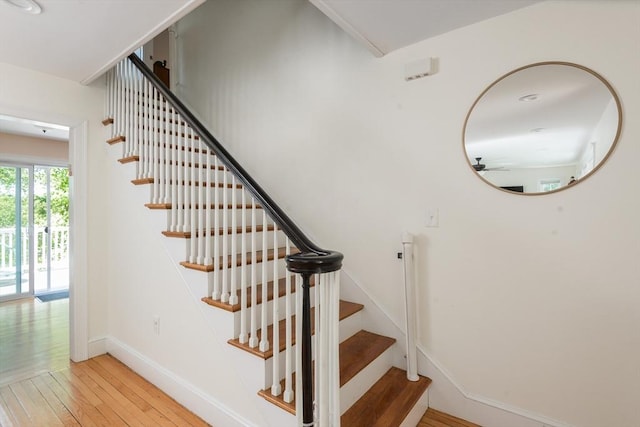 stairs featuring hardwood / wood-style floors, ceiling fan, and baseboards
