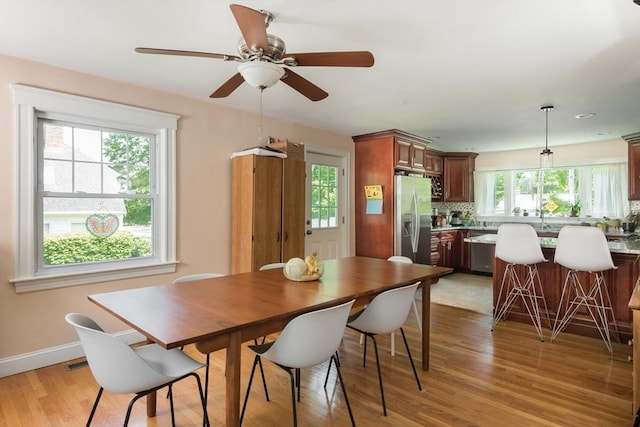 dining room with light wood finished floors, ceiling fan, and baseboards
