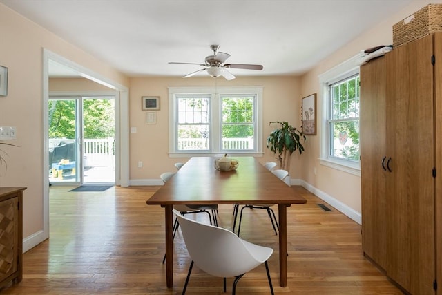 dining space with baseboards, a ceiling fan, and light wood finished floors