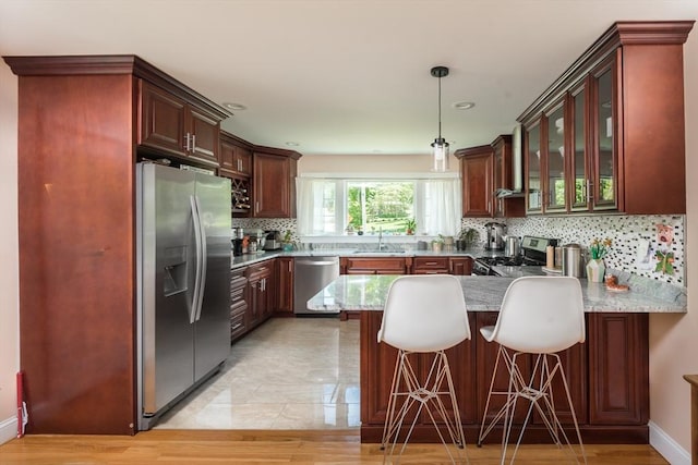 kitchen with appliances with stainless steel finishes, a sink, a peninsula, glass insert cabinets, and decorative backsplash