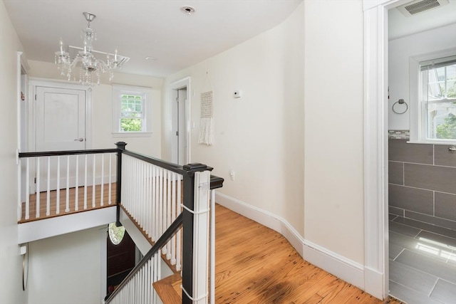 hall with an upstairs landing, plenty of natural light, and a chandelier