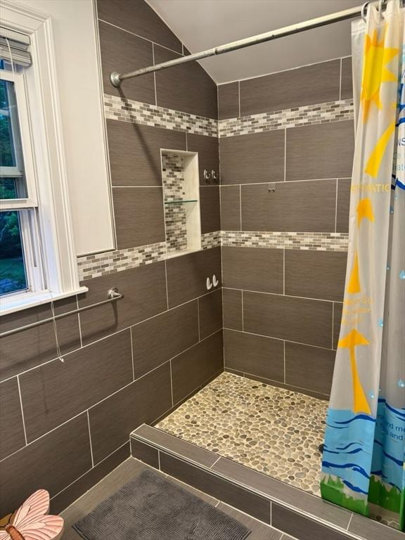bathroom featuring tiled shower, vaulted ceiling, and tile patterned floors