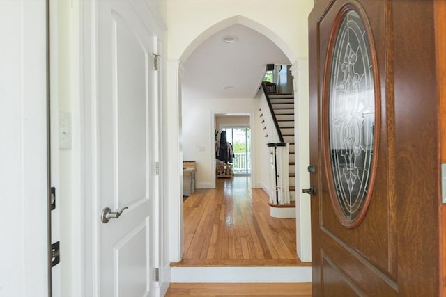 foyer entrance with hardwood / wood-style floors, arched walkways, stairs, and baseboards
