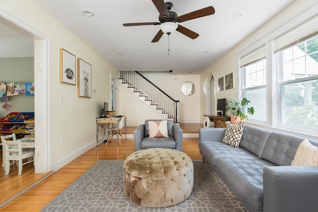 living area featuring light wood-style flooring, stairs, ceiling fan, baseboards, and recessed lighting