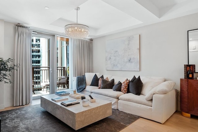 living room with a chandelier, a tray ceiling, and wood finished floors