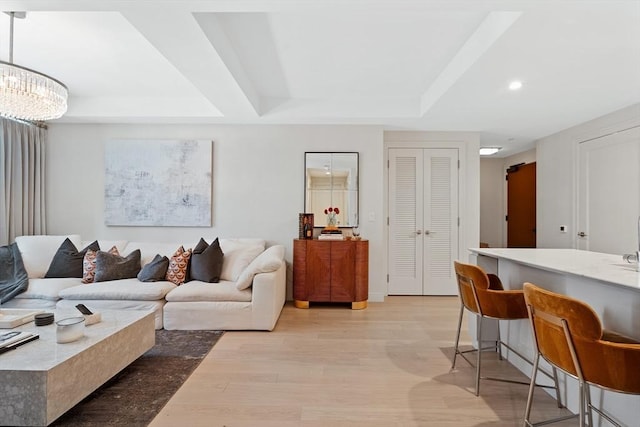 living room featuring light wood-type flooring, a tray ceiling, and recessed lighting