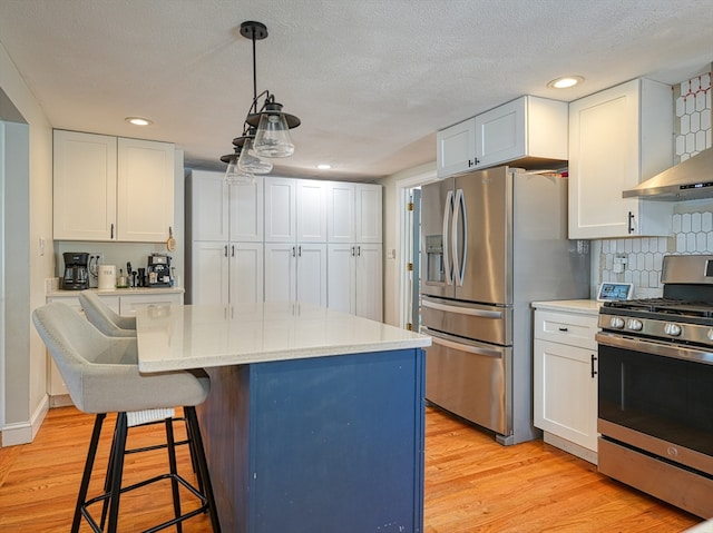 kitchen with tasteful backsplash, a kitchen island, white cabinetry, stainless steel appliances, and light hardwood / wood-style flooring