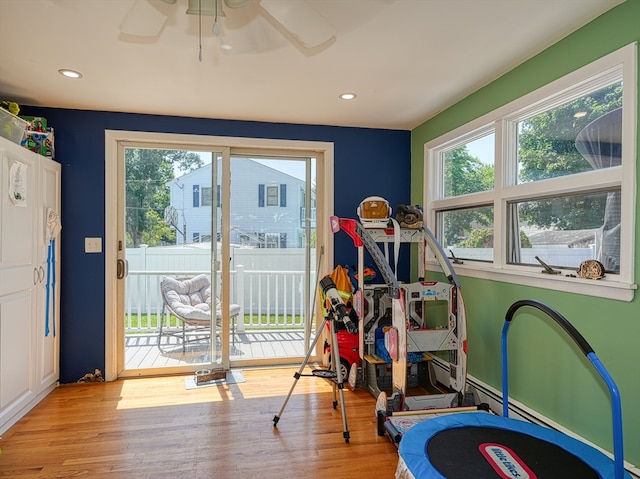 rec room with light hardwood / wood-style floors, a healthy amount of sunlight, and ceiling fan